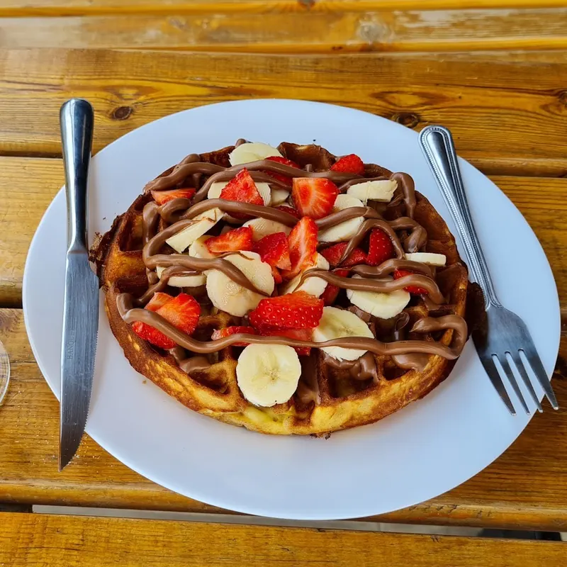 Waffle with Nutella, strawberries and banana on a wooden table